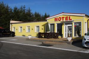 un edificio giallo con un cartello di un motel in un parcheggio di Motel Kochlice a Kochlice