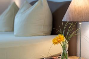 a vase with a yellow flower on a table next to a bed at Ein Bett im Norden in Fehmarn