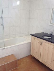 a bathroom with a bath tub and a sink at Huisje Finn, met grote tuin en veel privacy in Dirkshorn