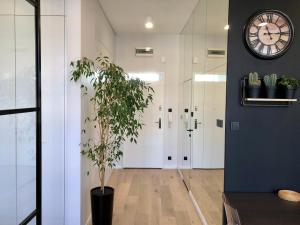 a hallway with a clock on the wall and a plant at Neon Loft Apartament Bukowskiego in Białystok +21 photos