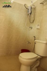 a bathroom with a toilet and a phone on the wall at Alinchlo Hotel in Legazpi