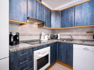 une cuisine avec des armoires bleues et des appareils blancs dans l'établissement Apartment Pueblo Panorama-1 by Interhome, à Benitachell