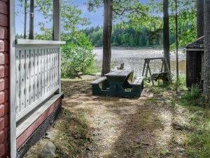 a picnic table and a swing in front of a lake at Holiday Home Haapalehto by Interhome in Nurmes