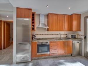 La cuisine est équipée d'armoires en bois et d'un réfrigérateur en acier inoxydable. dans l'établissement Apartment Zephyrus by Interhome, à Dénia