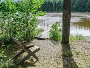 a bench sitting next to a tree next to a lake at Holiday Home Haapalehto by Interhome in Nurmes