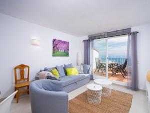 ein Wohnzimmer mit einer blauen Couch und einem Balkon in der Unterkunft Apartment Pueblo Panorama-1 by Interhome in Benitatxell