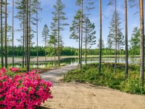 a path through a forest with pink flowers at Holiday Home Kielo by Interhome in Pertunmaa