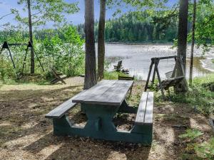 a picnic table next to a lake with a swing at Holiday Home Haapalehto by Interhome in Nurmes