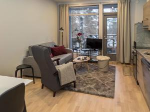 ein Wohnzimmer mit einer Couch und einem Sessel und einem Fernseher in der Unterkunft Holiday Home Ylälänsi 3 as 11 by Interhome in Ylläsjärvi