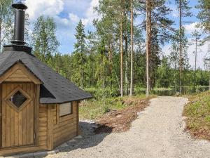 a small building with a black roof on a dirt road at Holiday Home Kurki by Interhome in Pertunmaa