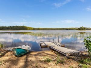 a boat on the shore of a lake with a dock at Holiday Home Kaarna by Interhome in Pertunmaa