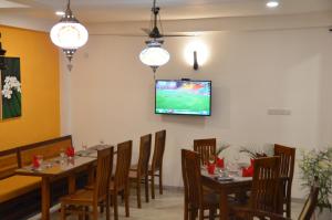 a dining room with tables and chairs and a tv on the wall at House On The Bend in Hiriketiya
