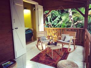 eine Veranda mit 2 Stühlen, einem Sofa und einem Tisch in der Unterkunft Ti coin paradis in Anse-Bertrand