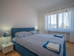una camera da letto con un letto con copriletto blu e una finestra di Apartment Damir by Interhome a Lovran (Laurana)