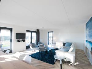 a living room with white furniture and a tv at Holiday Home Oesterdam Resort-1 in Tholen