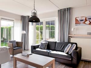 a living room with a black leather couch at Holiday Home Bungalowpark It Wiid by Interhome in Eernewoude