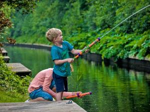 Ein kleiner Junge, der auf einem Steg mit einer Angelrute steht. in der Unterkunft Holiday Home Bungalowpark It Wiid by Interhome in Eernewoude