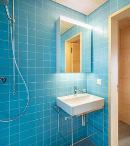 uma casa de banho em azulejos azuis com um lavatório e um espelho em Labbrunnu in den Walliser Alpen em Rosswald