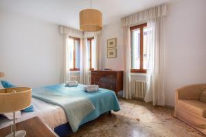 een slaapkamer met een bed, een stoel en ramen bij Ca degli Angeli in Venetië