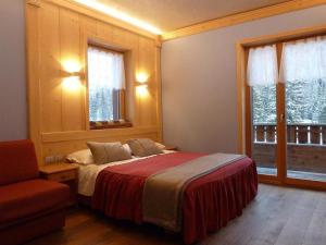 a bedroom with a bed and a chair and windows at Albergo Chalet Lago Antorno in Misurina