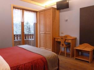 a bedroom with a bed and a desk and a window at Albergo Chalet Lago Antorno in Misurina