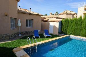 ein Pool mit zwei blauen Stühlen neben einem Haus in der Unterkunft Golf & Playa II in Oliva