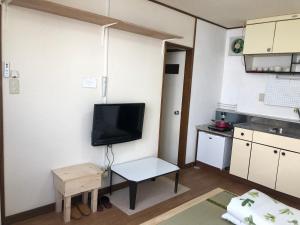 a small kitchen with a tv and a small table at Happy Apartment in Sapporo