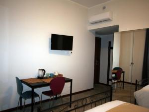 ein Zimmer mit Tisch und Stühlen und einem Fernseher an der Wand in der Unterkunft SanSiroFiera Rooms in Mailand