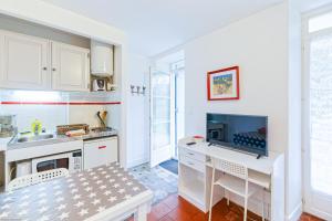 uma cozinha com armários brancos e uma secretária com uma televisão em Appart'Hôtel Bellevue em Baiona