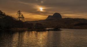 a sunset over a body of water with a mountain at North Coast 500 Pods in Achmelvich
