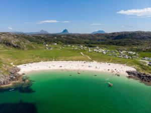 an aerial view of a beach with people in the water at North Coast 500 Pods in Achmelvich