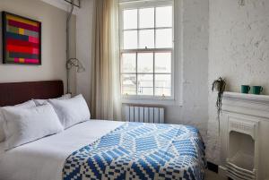 Schlafzimmer mit einem Bett mit einer blauen und weißen Bettdecke in der Unterkunft The Buxton in London