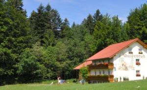 a white building with a red roof in a field at Pension Waldesruh in Sankt Oswald