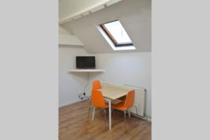 Zimmer mit einem Tisch und zwei orangenen Stühlen in der Unterkunft Top Studio Marolles in Brüssel