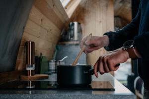 a person stirring a pot with a wooden spoon at North Coast 500 Pods in Achmelvich