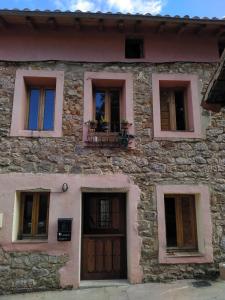 - un bâtiment en pierre avec des fenêtres, une porte et un balcon dans l'établissement Albergue el Hacedor, à La Aldea del Portillo de Busto