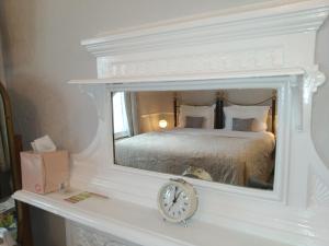 um quarto com uma cama e um relógio sobre uma lareira em Anton Guest House Bed and Breakfast em Shrewsbury