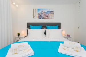 um quarto com uma cama azul e 2 toalhas brancas em BestVillas Foz do Minho em Caminha