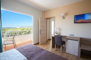 1 dormitorio con cama, escritorio y ventana en Invisa Ereso All Inclusive, en Es Canar