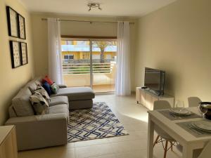 uma sala de estar com um sofá e uma televisão em Apartamento T2 com piscina em Conceição e Cabanas de Tavira em Tavira