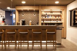 a kitchen with a bar with four stools at Holiday Inn Express - Sindelfingen, an IHG Hotel in Sindelfingen