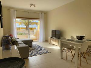 een woonkamer met een tafel en een bank bij Apartamento T2 com piscina em Conceição e Cabanas de Tavira in Tavira