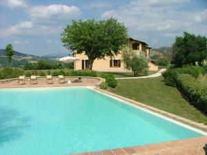 a large swimming pool with a house in the background at Agriturismo Castagna Alta in Valfabbrica