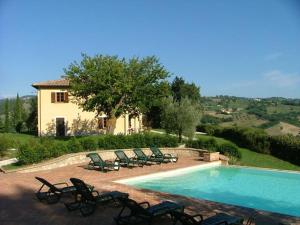 a swimming pool with chairs and a house at Agriturismo Castagna Alta in Valfabbrica