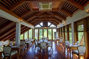 a dining room with tables and chairs and windows at The Hotel by the Red Canal in Mandalay