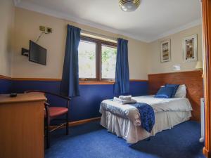 a bedroom with a bed and a desk and a window at Findlay's in Fraserburgh