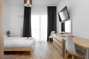 a bedroom with a bed and a desk with a television at Wola Chic Studios in Warsaw