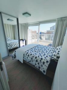 ein Schlafzimmer mit einem Bett und einem großen Fenster in der Unterkunft Penthouse met groot terras Oostende in Ostende