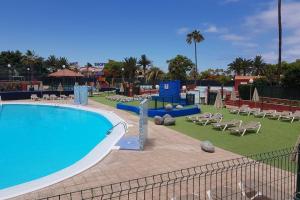 une grande piscine avec des chaises et une aire de jeux dans l'établissement Sonora Aircon Bungalow 121, à Maspalomas