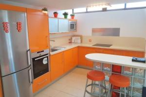 cocina con armarios naranjas, mesa y taburetes en Sonora Aircon Bungalow 121 en Maspalomas